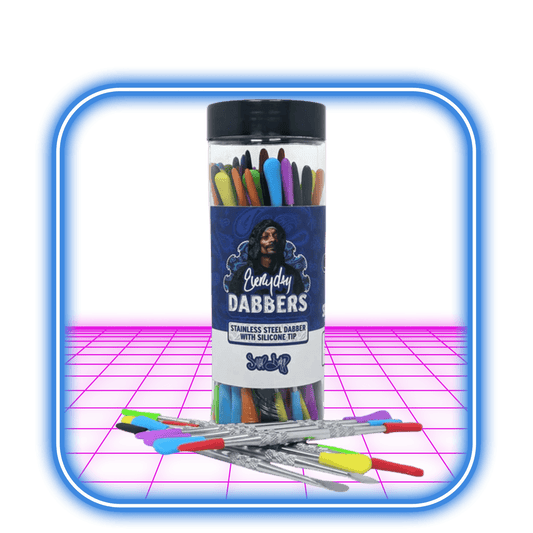 The Dogg Lbs | Everyday Wax Dabber av Dogg Lbs visas i en färgglad behållare, med flera rostfria dabbers med silikontipp anordnade framför. Den neonrosa bakgrunden har en blå dubbelfodrad ram.