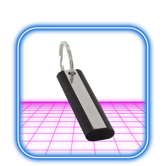 PAX 2/3 Multi-Tool från PAX, med ett metalliskt centrum i rostfritt stål och svarta kanter på en silvernyckelring, vilar på en ljusrosa abstrakt yta med en blå rundad fyrkantig kant.